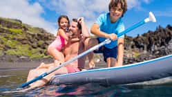 Mann mit Kindern auf SUP im Wasser