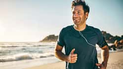 Läufer am Strand mit Kopfhörern Läufer am Strand mit Kopfhörern