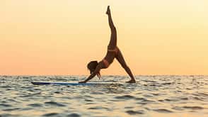 A young woman is doing Sup yoga on the paddle board at the ocean. A young woman is doing Sup yoga on the paddle board at the ocean.