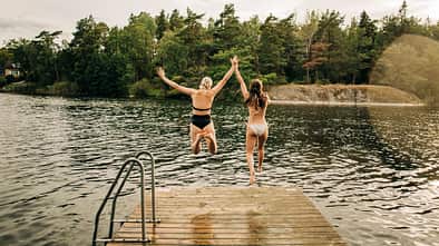 Zwei Frauen springen in den See - Sommerurlaub in Schweden