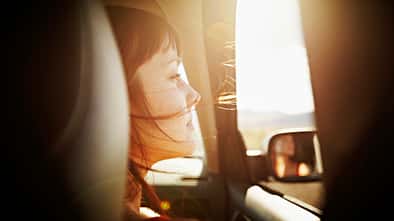 Woman with hair blowing looking out window of car