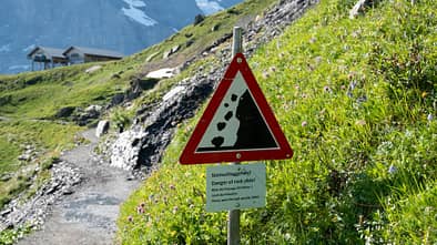 Steinschlaggefahr in den Alpen - Schild auf Wanderweg