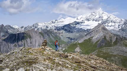 Female mountaineer on hiking trail with cairn, behind glaciated and snow-covered summit of the Großglockner, Wiener Höhenweg, Schober group, Hohe Tauern National Park, Carinthia, Austria - Stock-Fotografie Großglockner, Wiener Höhenweg, Schober-Gruppe, Hohe Tauern