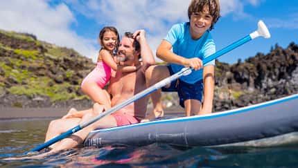 Mann mit Kindern auf SUP im Wasser
