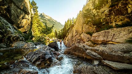 Adventurer standing in stream among mountains