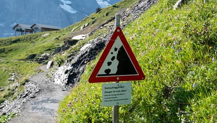 Steinschlaggefahr in den Alpen - Schild auf Wanderweg