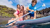 Mann mit Kindern auf SUP im Wasser