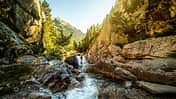 Adventurer standing in stream among mountains